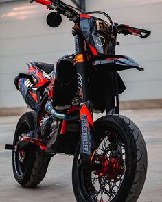 a red and black dirt bike parked in front of a building with graffiti on it