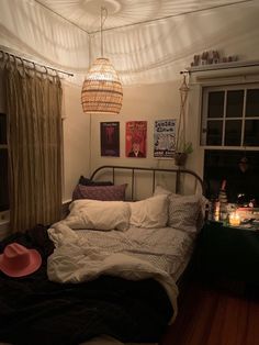 a bed room with a neatly made bed next to a window and a light hanging from the ceiling