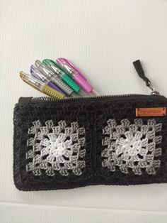 a crocheted pencil case with markers and pens in it