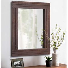 a mirror sitting on top of a wooden table next to a vase with flowers in it