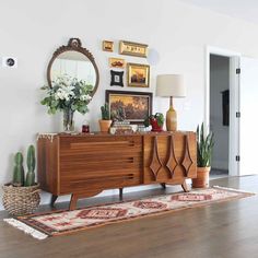 a wooden dresser sitting on top of a hard wood floor next to potted plants