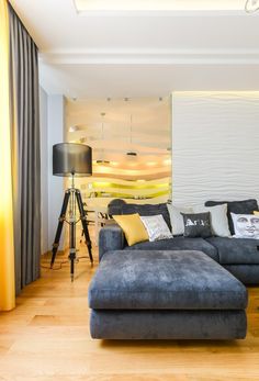 a living room filled with furniture next to a tall wall mounted painting on the wall