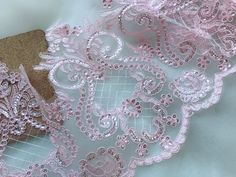 pink and white lace on fabric next to a piece of brown paper