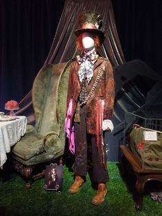 a man dressed up in costume standing next to a bed and table with furniture on it