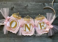 two pink and gold princess crowns on top of each other with the word one printed on them