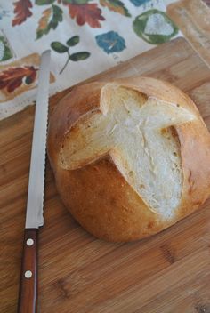 a loaf of bread sitting on top of a wooden cutting board next to a knife