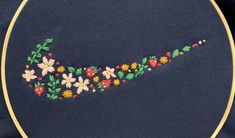 a close up of a embroidery design on a blue shirt with flowers in the shape of a swoob