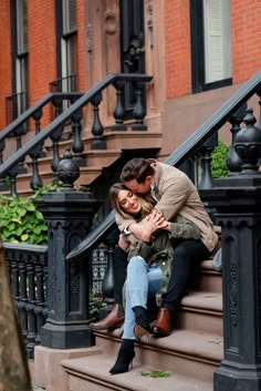 a man and woman sitting on the steps of an apartment building with their arms around each other