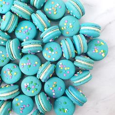 blue macaroons with sprinkles are on a white marble countertop