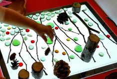 a child touching the frosting on a cake with pinecones and candy balls