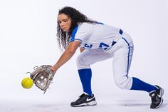 a woman in white and blue baseball uniform holding a yellow ball