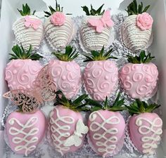 a box filled with pink and white chocolate covered strawberries next to butterfly wings on top of each strawberry