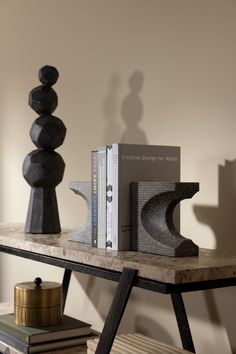 two books are sitting on a table next to some stacked rocks and a bookend