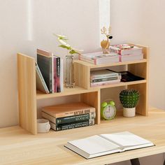 a wooden shelf with books and other items on it next to a plant in a vase