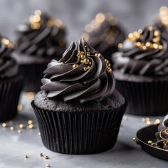 cupcakes with chocolate frosting and gold sprinkles on a table