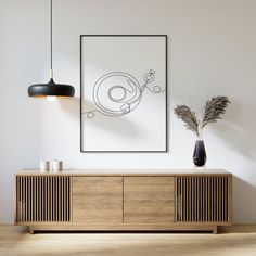 an abstract black and white painting hangs on the wall above a wooden sideboard in a modern living room