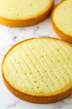 three yellow cakes sitting on top of a white counter next to each other with holes in the middle