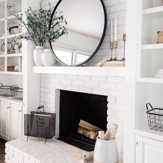 a living room with a white fireplace and mirror on the mantel, along with other decor items