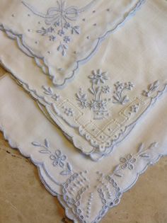 three white handkerchiefs with embroidered flowers on them