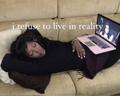 a woman is laying on the couch with her laptop