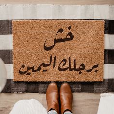 a person standing in front of a door mat with the words arabic written on it