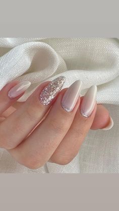 a woman's hand with some white and silver nail polishes on her nails