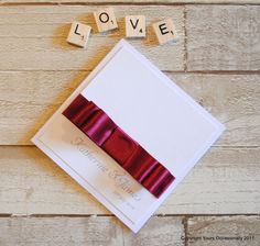 the word love spelled with scrabbles next to a red ribbon and bow