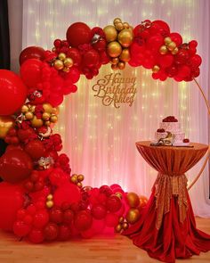 a red and gold birthday party is set up with balloons, streamers, and a cake