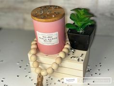 a pink candle sitting on top of a wooden block next to a small potted plant