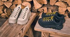 two pairs of black and yellow shoes sitting on top of wooden logs next to each other