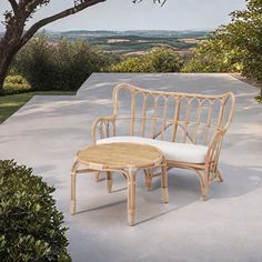 a wooden bench sitting on top of a cement floor next to a lush green field