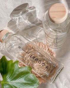 two empty water bottles sitting on top of a white cloth next to a green plant