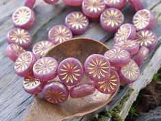 a wooden spoon sitting on top of a table covered in purple and gold jewelry pieces