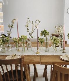 the table is set with many vases and flowers on it, along with candles