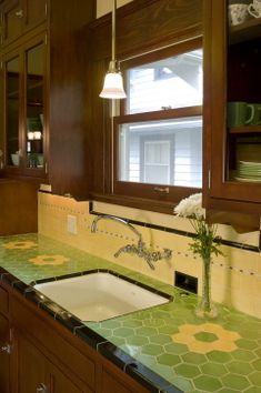 a kitchen with wooden cabinets and green counter tops, along with a white sink in the center