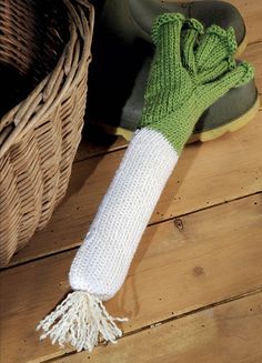 a pair of green and white gloves sitting on top of a wooden floor next to a basket