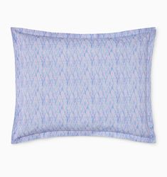 a blue and white pillow sitting on top of a bed