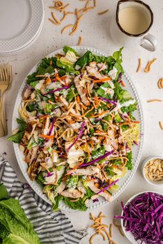 a salad with chicken, lettuce and carrots on a plate next to a cup of coffee