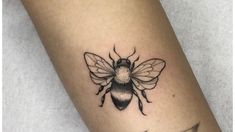 a small bee tattoo on the left forearm and right leg, it is black and white