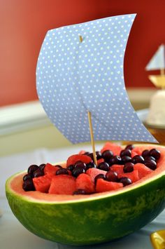 a watermelon boat filled with black olives and cherries on a table