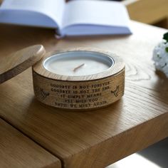 a candle sitting on top of a wooden table next to an open book and flowers