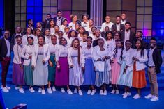 a group of people standing next to each other in front of a blue stage backdrop