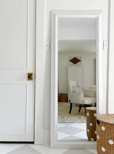 a white door with polka dot baskets in front of it and a mirror on the wall