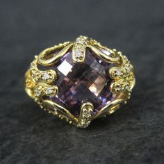 This stunning estate ring is gold vermeil over sterling silver. It features a faceted amethyst, estimated to be around 6 carats, accented by genuine diamonds. The face of this ring measures 5/8 of an inch north to south with a rise of 9mm off the finger. Size: 8 The designers hallmark is JH but I cannot seem to identify who that is. Condition: Flawless Exquisite Yellow Gold Amethyst Ring With Accent Stones, Luxury Amethyst Ring With Prong Setting, Luxury Yellow Gold Amethyst Ring With Prong Setting, Luxury Purple Diamond Ring For Formal Occasions, Luxury Yellow Gold Amethyst Ring With Gemstone Accents, Luxury Amethyst Diamond Ring For Gift, Luxury Hallmarked Amethyst Collectible Ring, Luxury Purple Rings For Anniversary, Luxury Purple Anniversary Rings