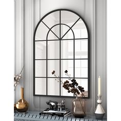 an arched window in the wall above a table with books and vases on it