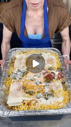 a woman in an apron is holding a tray with food on it and she has her hands over the pan