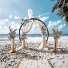 an outdoor wedding setup on the beach with blue flowers and white draping over it