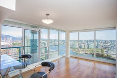 an empty room with wooden floors and large windows overlooking the cityscape in the distance