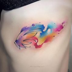 a woman's stomach with colorful watercolor tattoos on her belly and the side