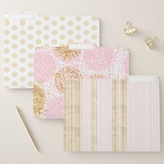 three pink and gold patterned file folders next to a pair of scissors